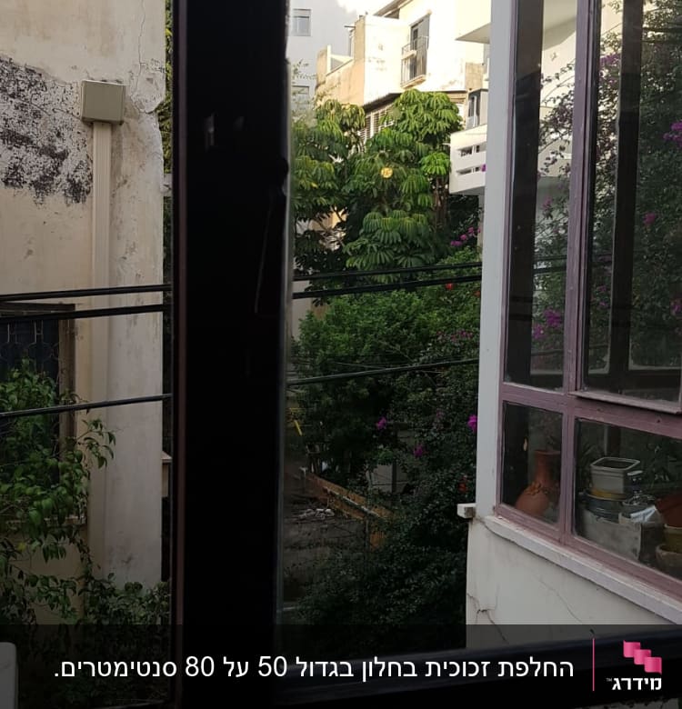 חלון זכוכית פתוח עם נוף חיצוני של בניינים ועצים